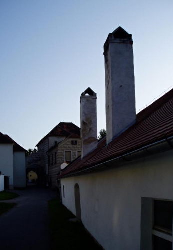 Vysoko ční komíny nízkých domků v okolí kláštera.