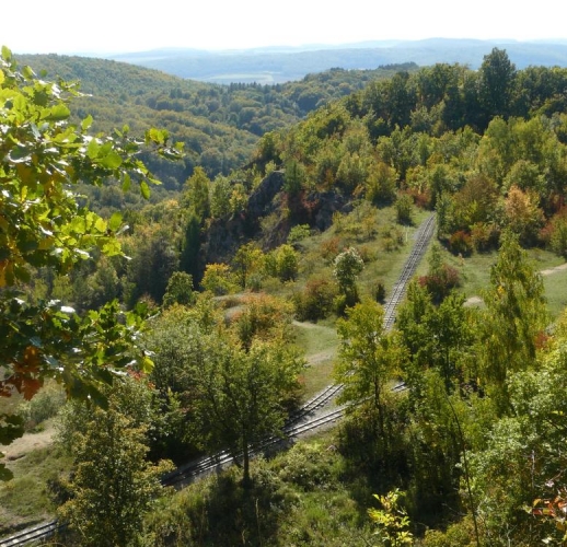 Pohled ze shora na železnici vybudovanou nadšenci a převážející místo vápencových balvanů pěkně natřásané kameny ve tvaru turisty.