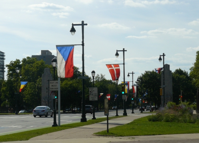 Vlajky podél ulice směřující od radnice k muzeu umění. Ulice je obklopena parky a muzei, což působí hezky.