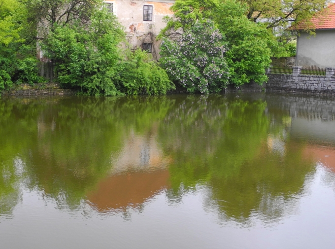 Klidná hladina rybníčku Ohrada zrcadlí jedno ze starých stavení, které by se v budoucnu mělo stát spolu s částí vesnice a zámeckým areálem památkovou zónou.