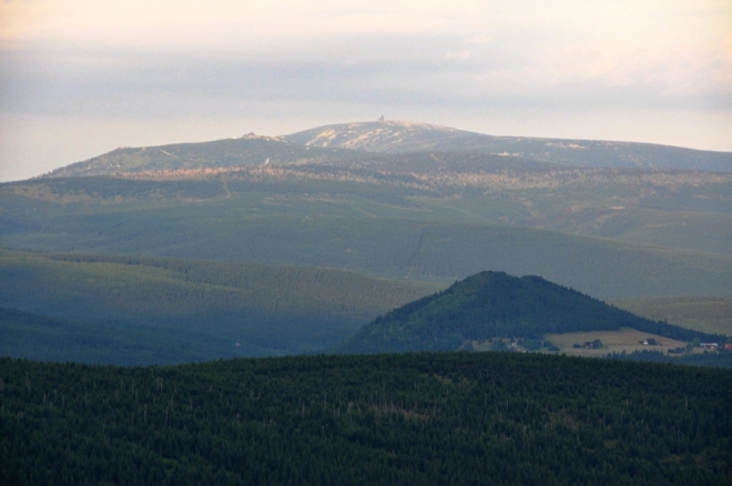 Bukovec více přitažený zoomem. Vysoko nad ním jsou vidět krkonošské Sněžné jámy a Vysoké Kolo (1 509 m n. m.).