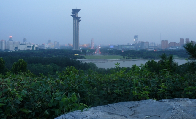 Výhled na Peking z balvanu na vrcholu kopečku v parku. Monstrózní rozhledna stále vévodí.