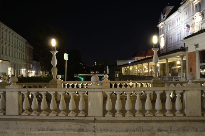 Pokud zde chcete přejít řeku Lublaňku (Ljubljanica), která zeširoka obtéká vrch s hradem, můžete si vybrat hned ze tří takřka souběžných mostů. Odtud vyplývá také název tohoto místa, Trojmostí (Tromostovje). Právě se díváme po směru toku řeky, kterou zde zprava lemuje dlouhá kolonáda.