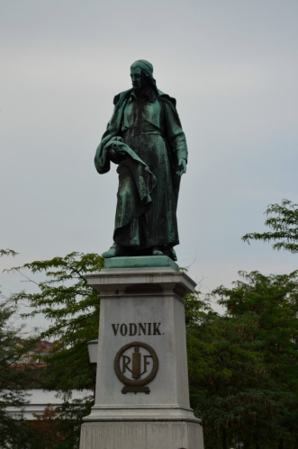Míjíme Vodnikův památník na Vodnikově náměstí (Vodnikov trg). Valentin Vodnik byl básník, publicista a průkopník slovinského jazyka, žil na přelomu 18. a 19. století.