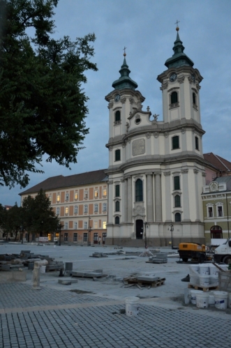 Vecpat objektiv do oka ochranného pletiva i našikmo nebyla žádná legrace, ale nakonec mám vyfocenou i dominantu náměstí, minoritní kostel. Druhou dominantou náměstí je nepříliš vzhledná, zřejmě socialistická budova, v níž sídlí Billa, ta je ale šikovně schována za stromy (mimo záběr vlevo).