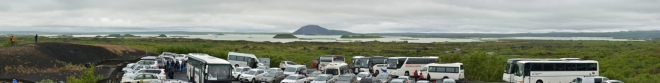 Po příchodu ze skalního města je parkoviště téměř zaplněné. Vzadu jezero Mývatn s pseudokrátery a charakteristickou horou Vindbelgjarfjall.