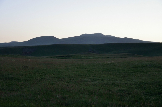 Na horizontu ozářeném vycházejícím sluncem nás vyhlíží vrchol Aždahak, v jehož blízkosti chceme strávit příští noc.