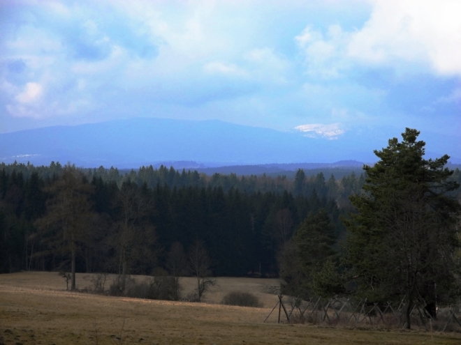 Vzdálená Smrčiná a zřejmě zasněžený vrchol Plechého, nejvyšší hory české strany Šumavy..