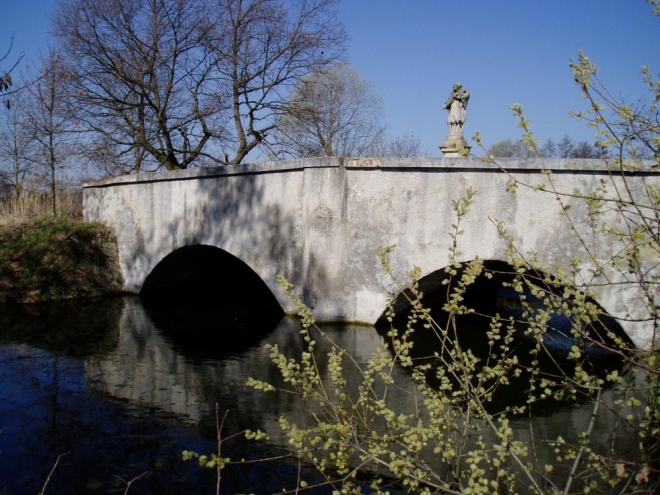Skutečně starobylou památkou ve městě Zlivi je dvouobloukový kamenný most z počátku 18. století přes Soudný potok, zdobený sochou sv. Jana Nepomuckého z roku 1724. A my se můžeme tímto mostem dostat od přírodních zajímavostí k těm kulturním.