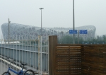 V Pekingu poté, co jsem vylezl z metra na stanici Olympic sports center. V pozadí je olympijský stadion Bird's nest (Ptačí hnízdo), v popředí plot okolo olympijského areálu. Poblíž se nacházela i bezpečnostní kontrola před vstupem do areálu. Tehdy jsem si myslel, že se tam i platí, a tak jsem olympijský areál obcházel.